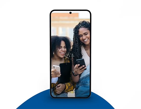 Deux jeunes femmes sourient en utilisant leur téléphone avec un forfait de type « conservez votre propre téléphone » de Bell