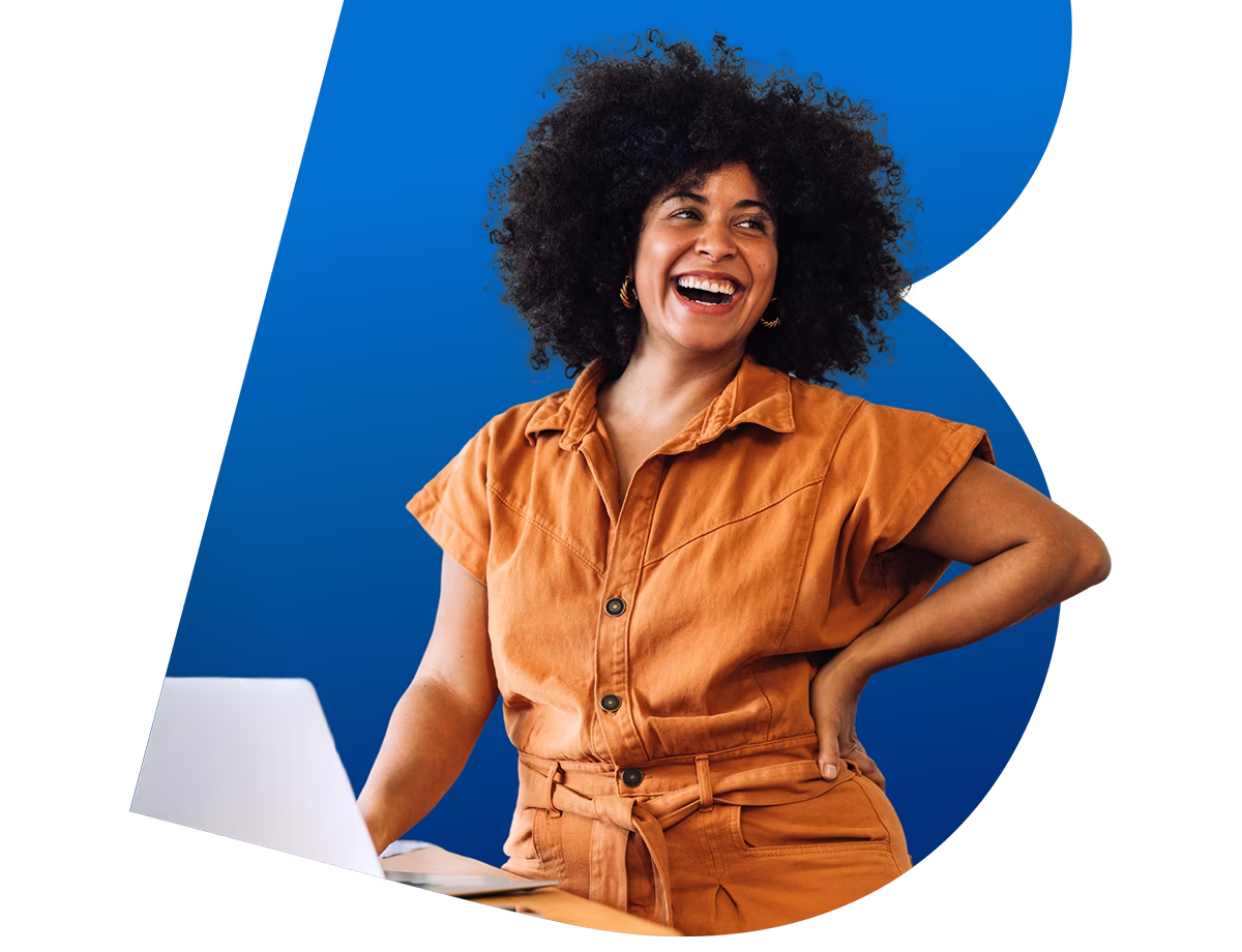 A woman smiling while working on a laptop.
