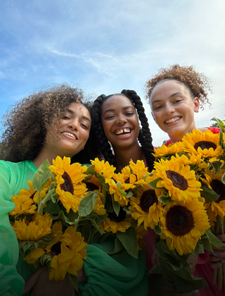 Selfie net et coloré de trois personnes tenant des fleurs.