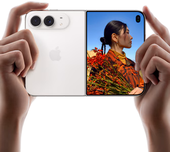 iPhone Duo, Star White colour, held by two hands in horizontal orientation, unfolded, left panel shows 48MP Dual Fusion rear cameras, right panel shows person getting their picture taken on outer display, the subject of the photo is able to see their face as their picture is getting taken using Duo Preview